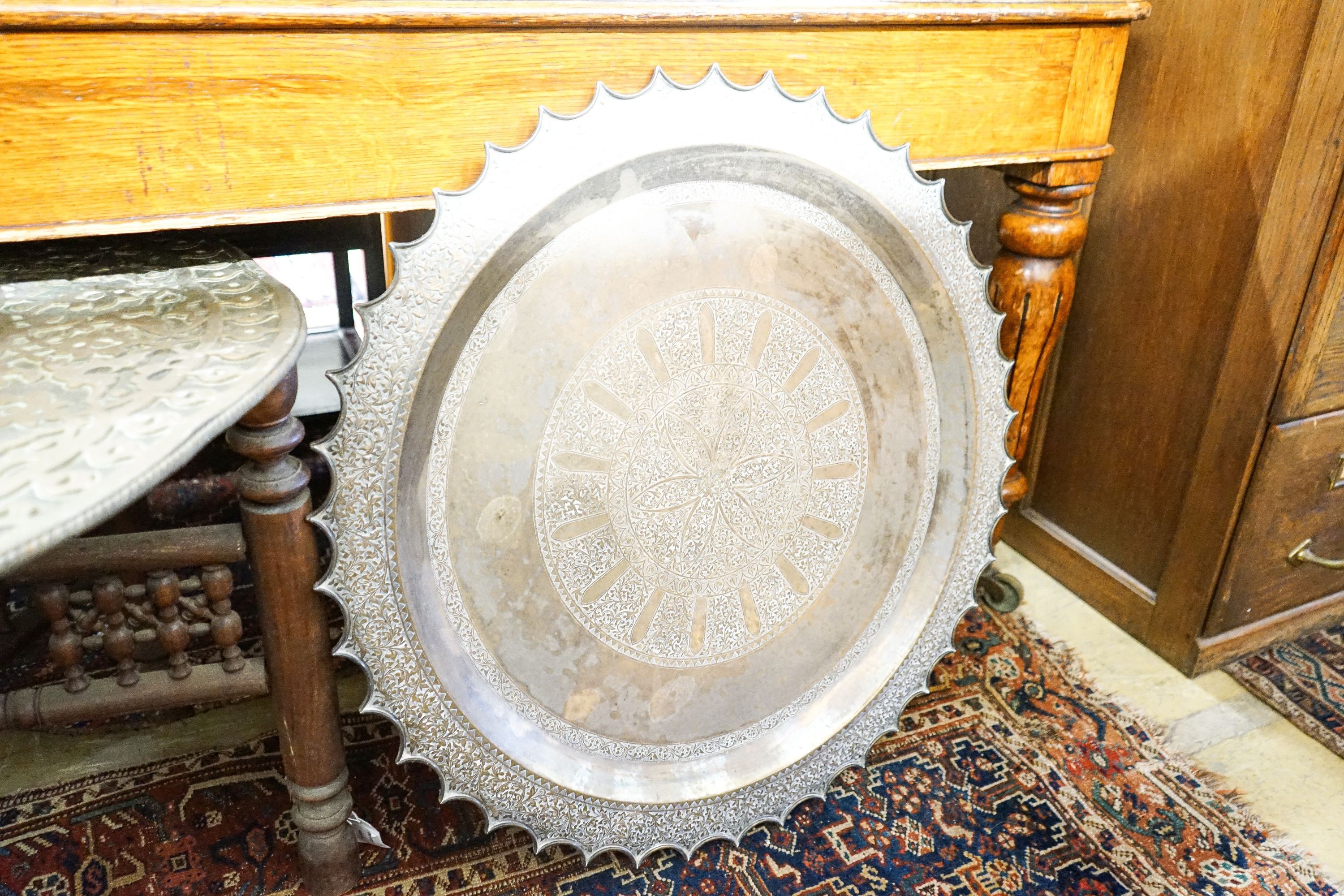 An Indian brass tray top table on folding stand, diameter 74cm, height 56cm together with a circular Indian brass tray